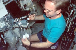 Mir-25 crewmember Andrew Thomas takes a Microbial Collection Device (MCD) sample for Water Experiment Kit VI (WEK VI) using a syringe pump. 